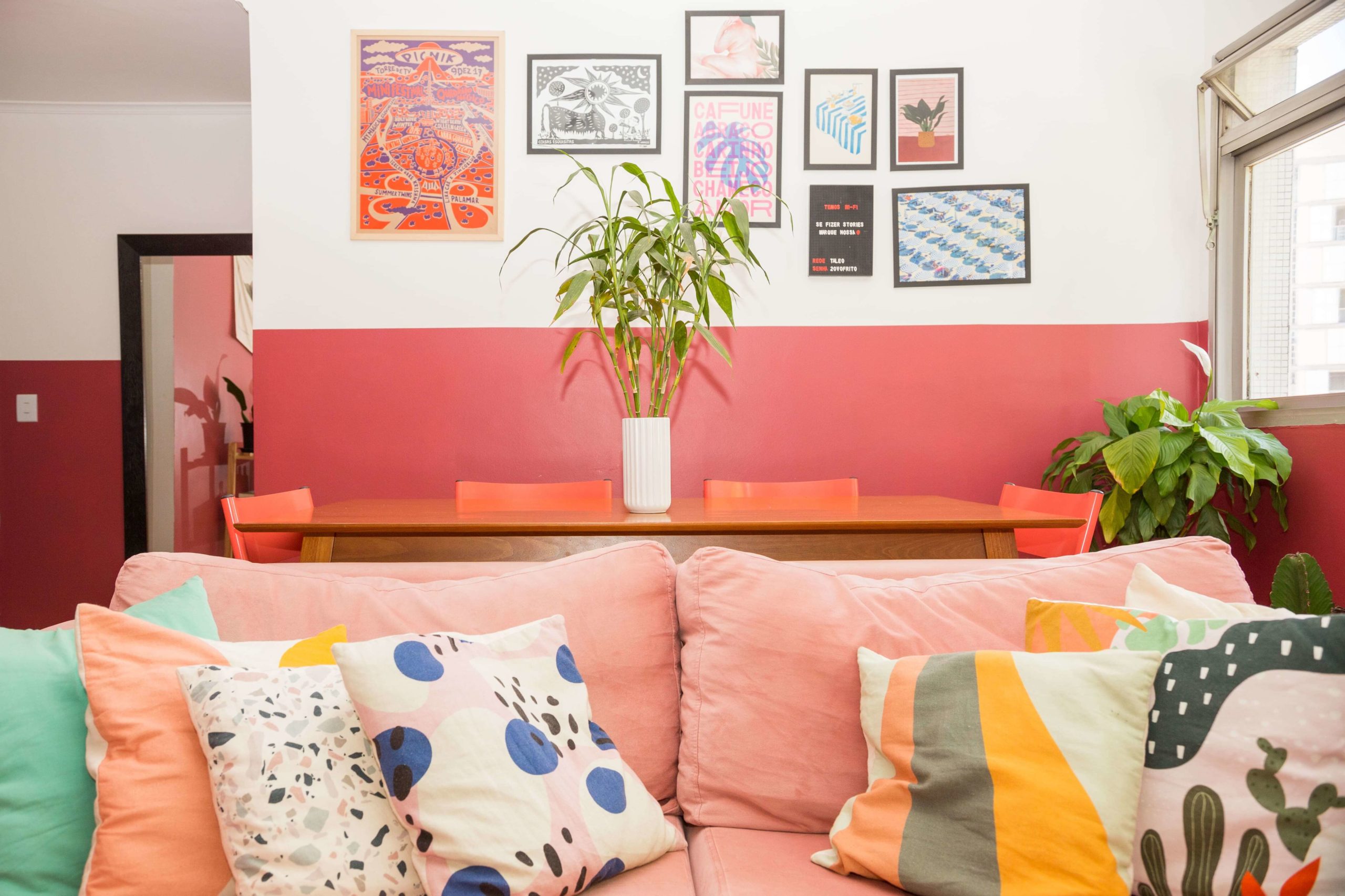 sala de apartamento co paredes pintadas de cor de rosa, quadros e sofá