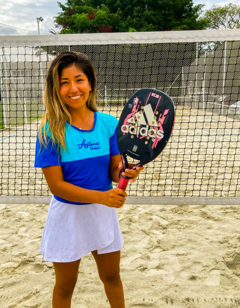 Professora de beach tennis Yessi Cordova segura uma raquete em uma quadra de areia