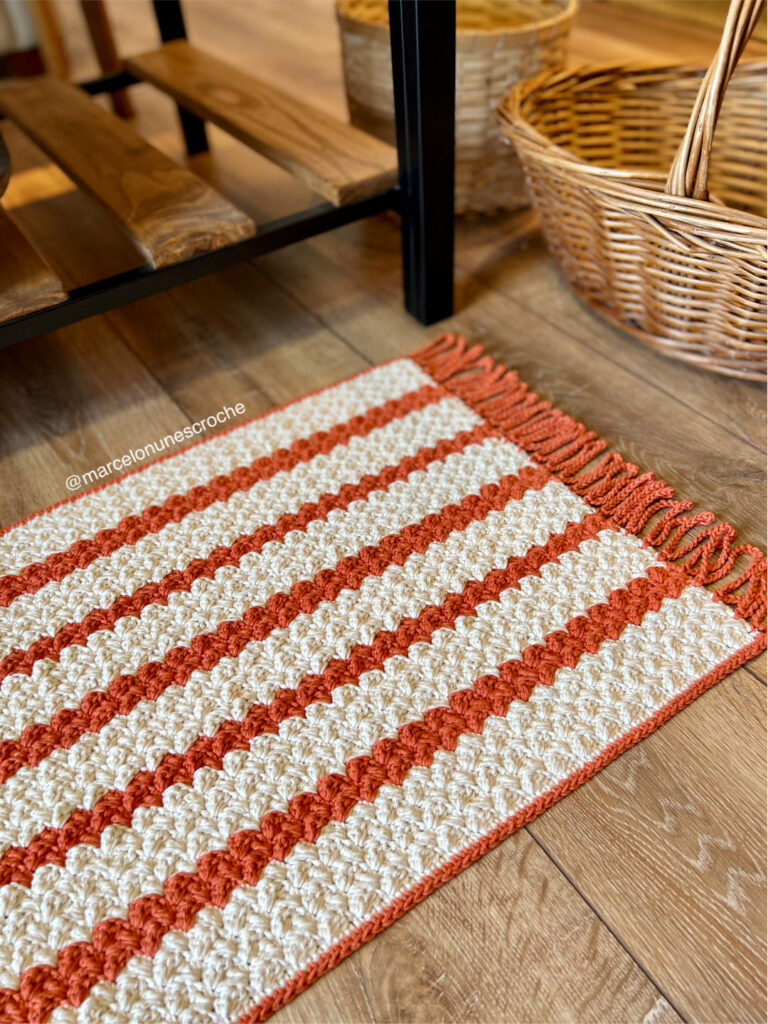 Tapete de crochê listrado nas cores laranja e cru, que pode ser feito em diferentes tamanhos 