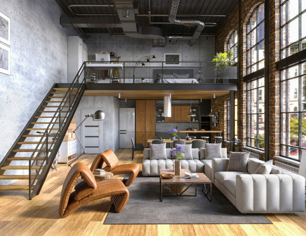 Loft industrial com mezanino, onde está o quarto. Embaixo, sofás e poltronas da sala, com grande janela na lateral e, ao fundo, a cozinha aberta