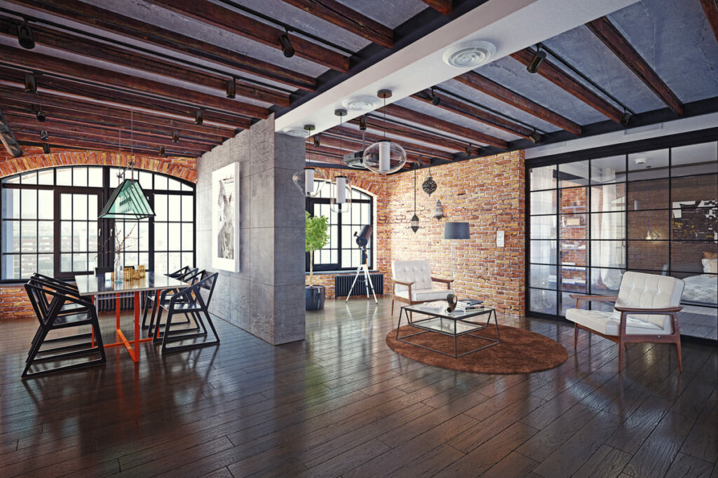 Lofts modernos podem contar com cômodos distintos e estruturas adicionais, além de decoração mais ousada. Nesse, as paredes de tijolo combinam com a sala tradicional, e as de cimento com a mesa de jantar moderna