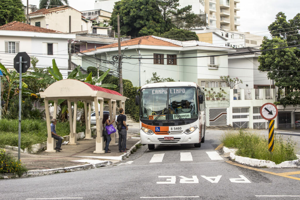 Ônibus circula pelas ruas secundárias da Lapa e pega passageiros em ponto em meio a casas