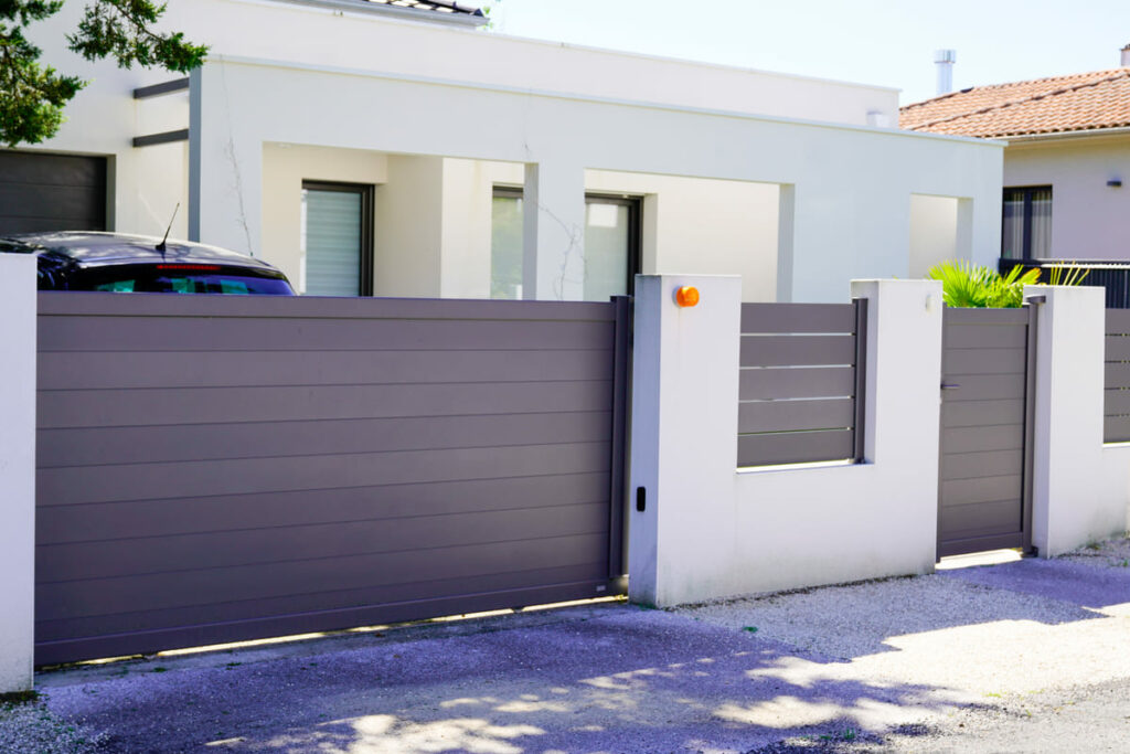 Fachada de casa branca com muro de madeira na entrada da garagem e porta de acesso
