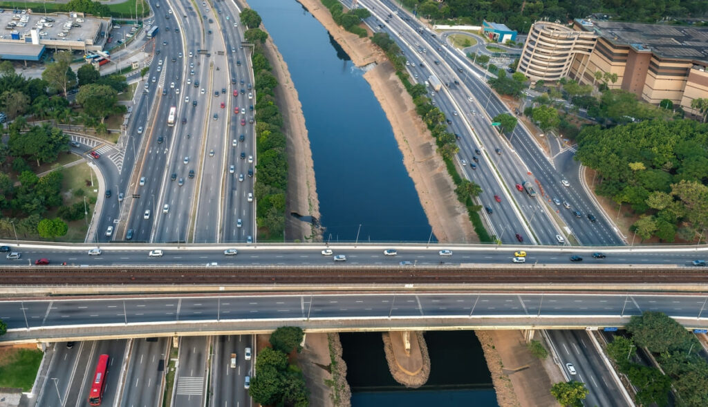 Vista aérea da Marginal Tietê, com vias e carros nas laterais, rio ao meio e ponte da Vila Guilherme que cruza os 3