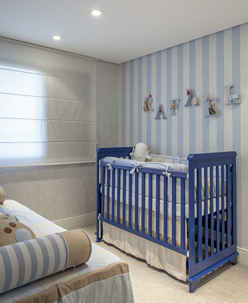 Decoração quarto bebê menino com papel de parede com listras brancas e azuis. Berço em azum escuro e cortina branca