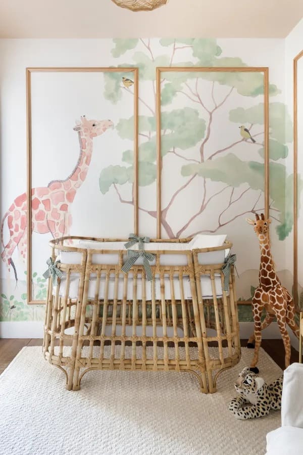 Quarto de bebê menino com tema safári tem paredes com desenhos de árvores e animais e berço rústico