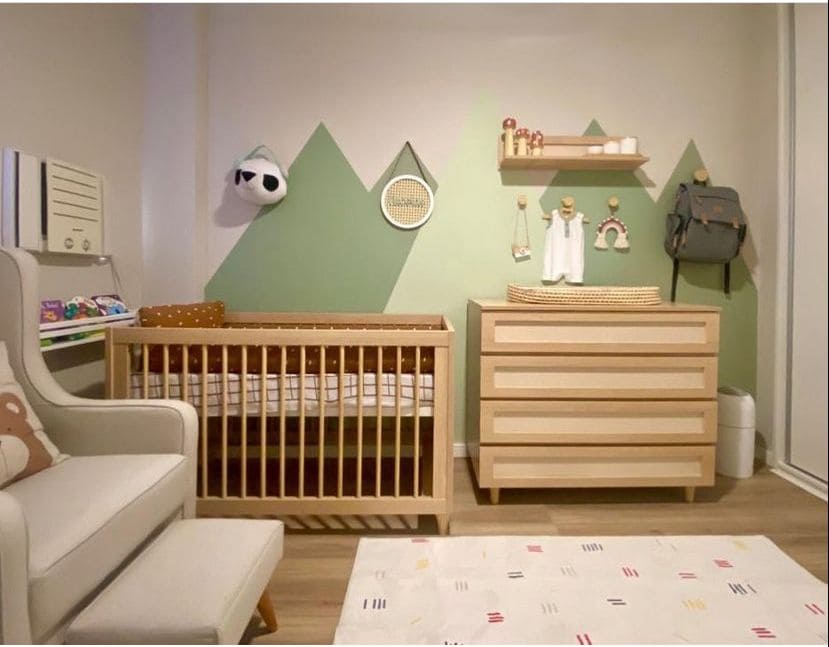 Decoração de quarto de bebê menino com tema montanhas. Na parede, as montanhas em tons de verde contrastam com os móveis de madeira clara 