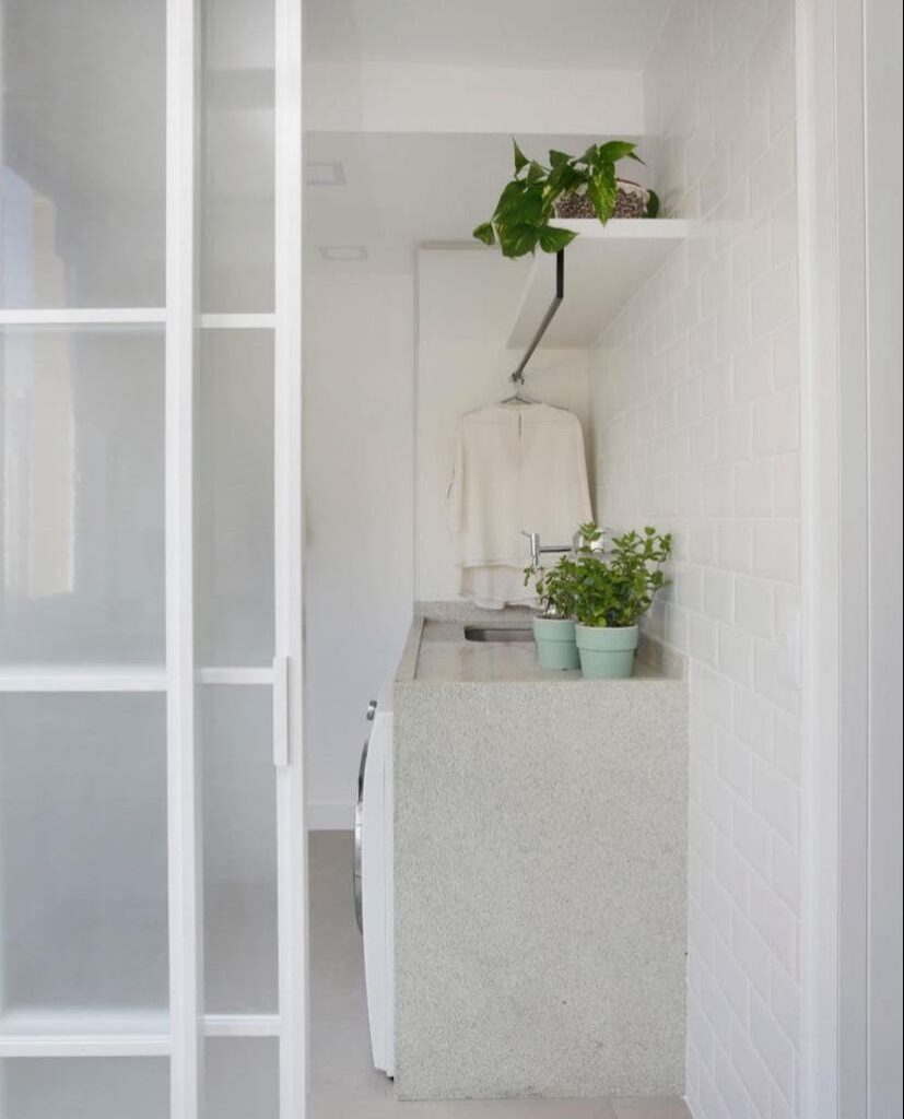 O vidro miniboreal tem textura e oferece privacidade na lavanderia, em tons claros e com plantas, aos moradores. 
